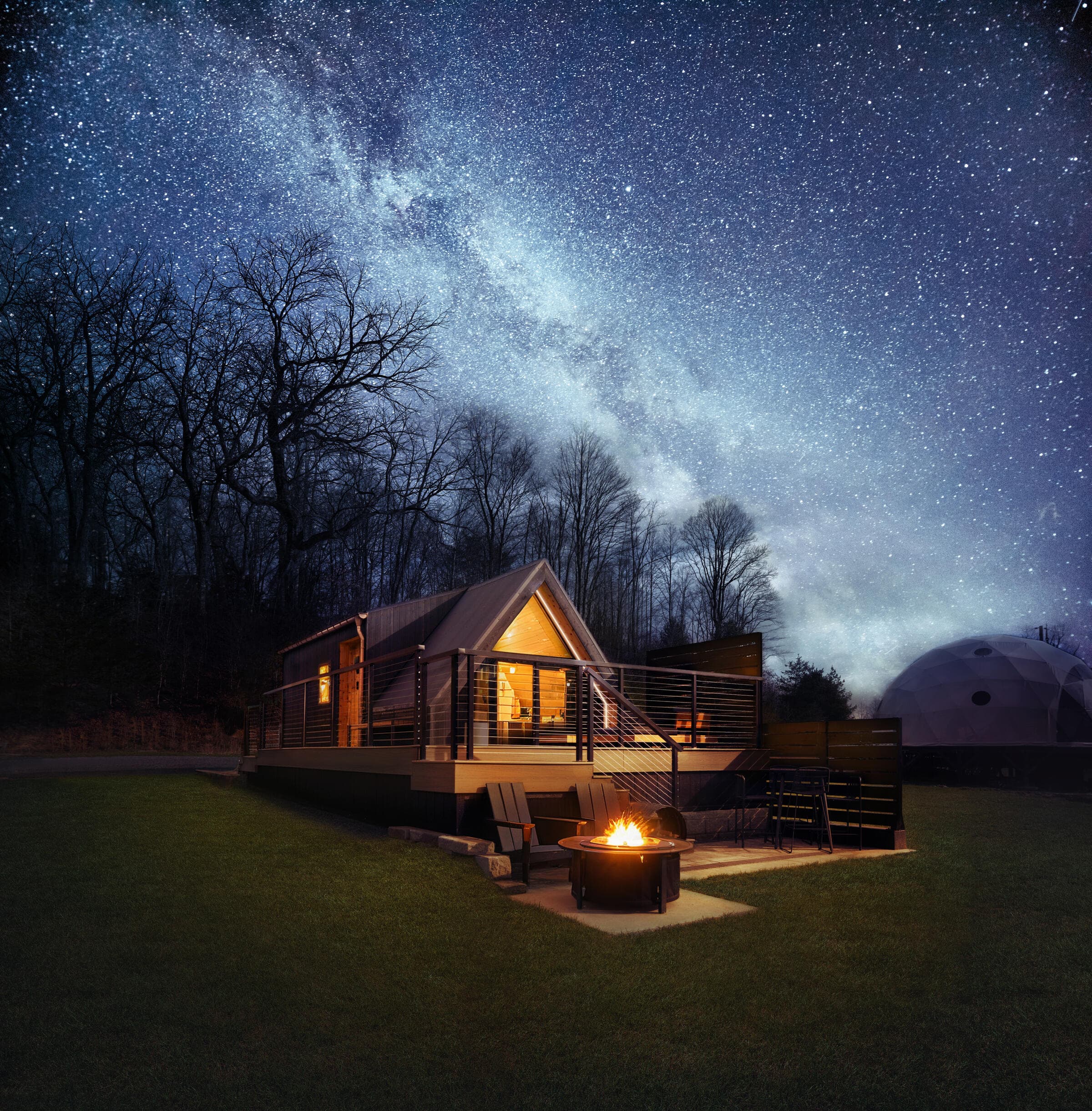 Cathedral Cabin at night under the Milky Way, with the fire pit lit