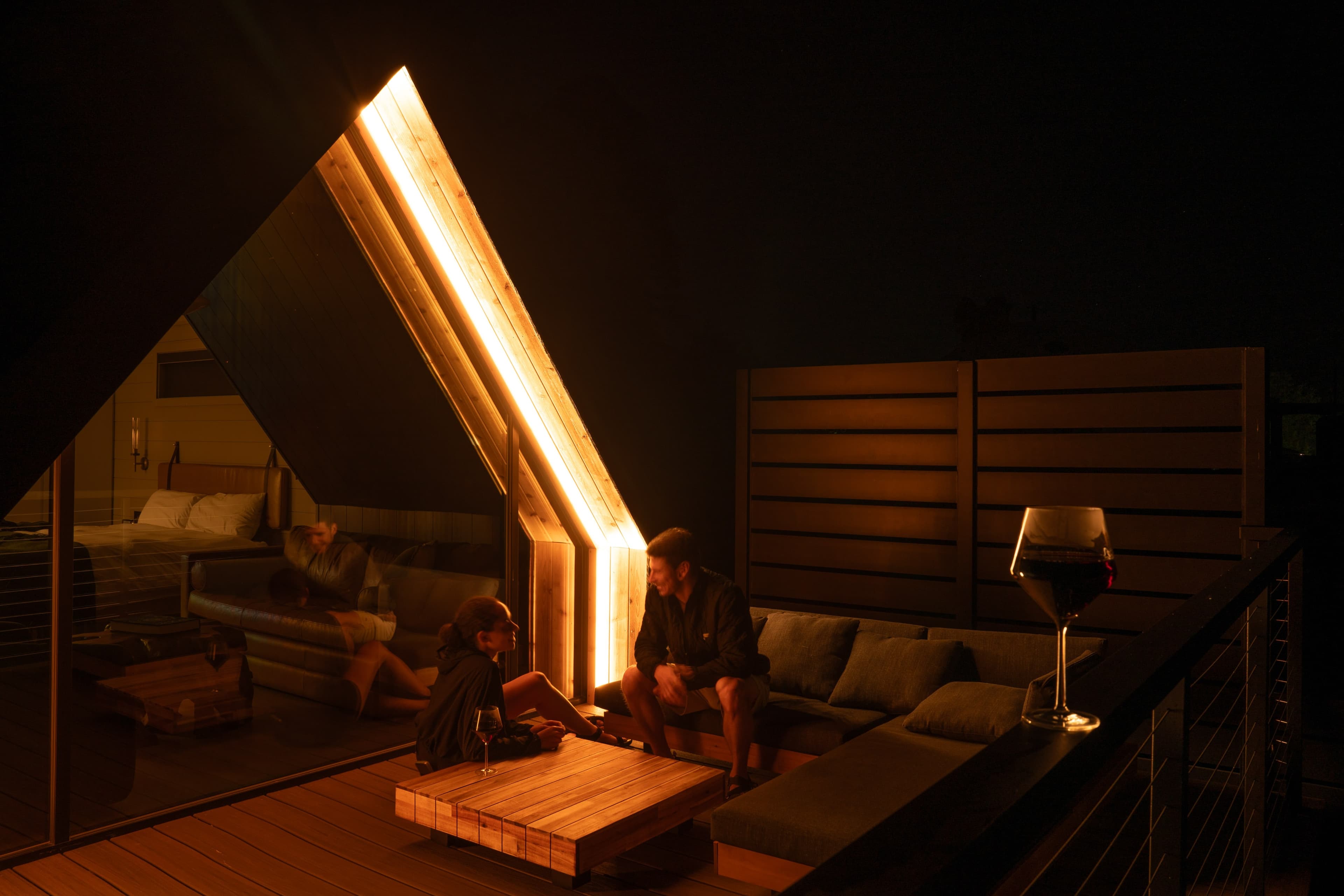Couple enjoying a conversation with a glass of wine on the deck of an A-frame.